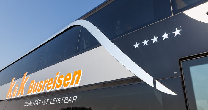 Schwarzer Bus mit K&K Busreisen-Logo, fünf weißen Sternen und Qualität ist leistbar auf der Seite.