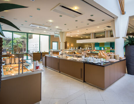 Modernes Hotelbuffet mit Brot, Gebäck und Frühstücksprodukten in einem hellen, geräumigen Essbereich.