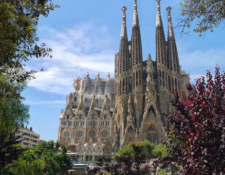 Außenansicht der Basilika La Sagrada Família in Barcelona mit hohen Türmen und komplizierter Architektur.