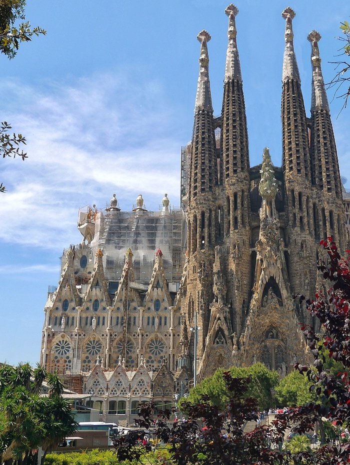 Außenansicht der Basilika La Sagrada Família in Barcelona mit hohen Türmen und komplizierter Architektur.