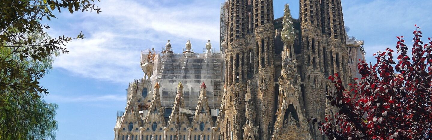 Außenansicht der Basilika La Sagrada Família in Barcelona mit hohen Türmen und komplizierter Architektur.
