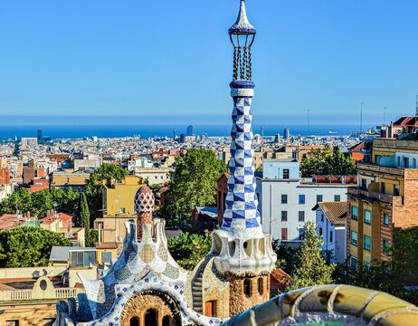 Park Güells bunte Mosaik-Türme und Stadtbild von Barcelona mit dem Mittelmeer im Hintergrund.