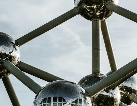 Nahaufnahme der metallischen Atomium-Struktur mit kugelförmigen Knotenpunkten vor einem bewölkten Himmel in Brüssel, Belgien.