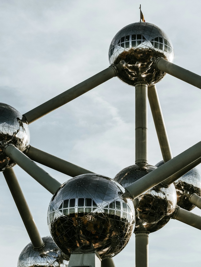Nahaufnahme der metallischen Atomium-Struktur mit kugelförmigen Knotenpunkten vor einem bewölkten Himmel in Brüssel, Belgien.