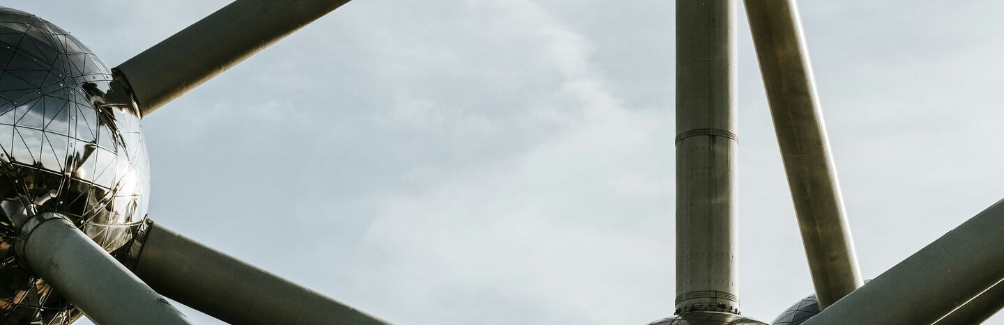 Nahaufnahme der metallischen Atomium-Struktur mit kugelförmigen Knotenpunkten vor einem bewölkten Himmel in Brüssel, Belgien.