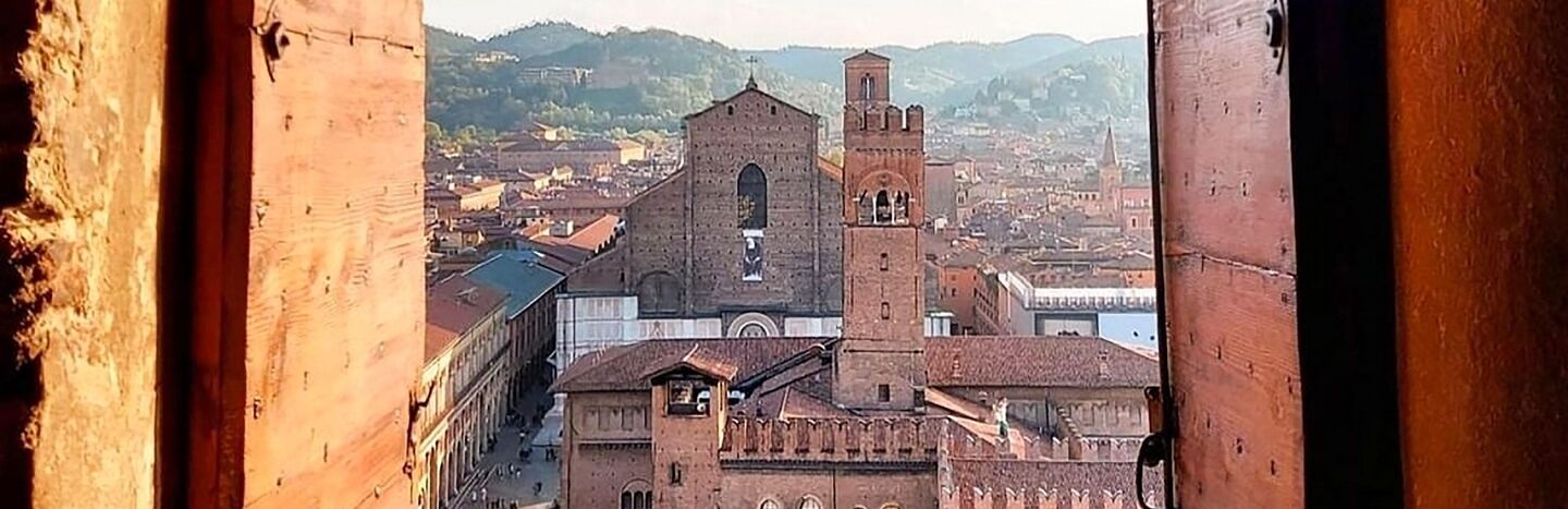 Eine Stadtlandschaft mit alten Gebäuden und Kirchtürmen, gesehen durch ein offenes Holzfenster.