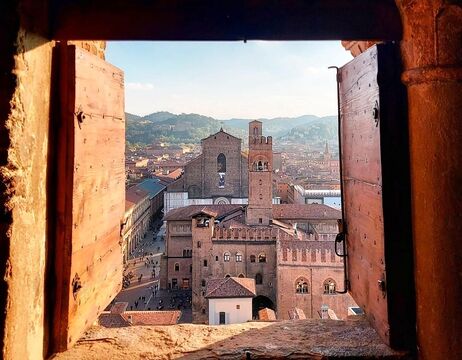 Eine Stadtlandschaft mit alten Gebäuden und Kirchtürmen, gesehen durch ein offenes Holzfenster.