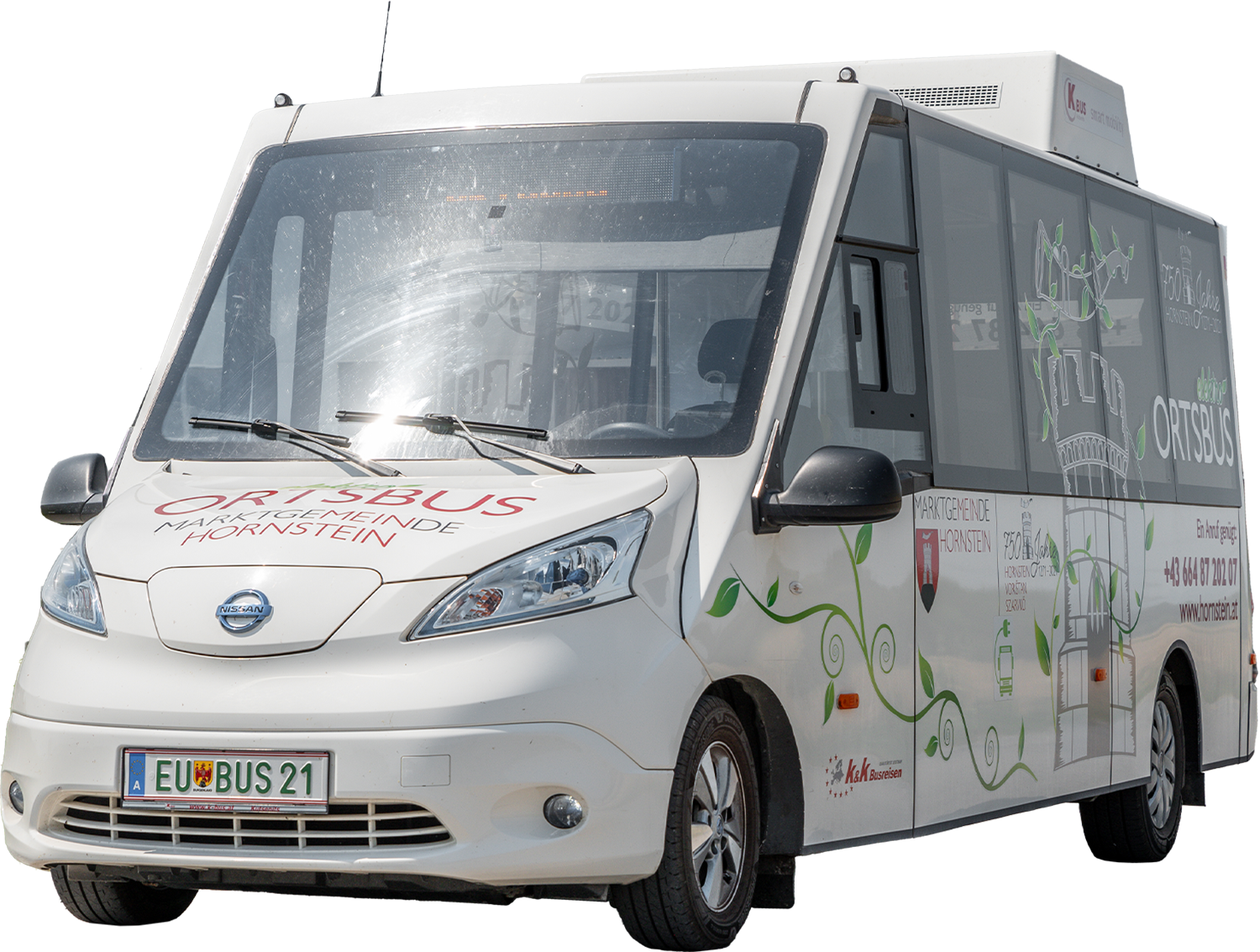 Kleiner weißer Elektro-Kleinbus mit Ortsbus-Schild und europäischem Nummernschild, der auf der Straße geparkt ist.