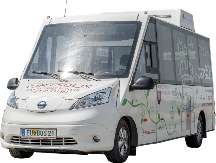 Kleiner weißer Elektro-Kleinbus mit Ortsbus-Schild und europäischem Nummernschild, der auf der Straße geparkt ist.