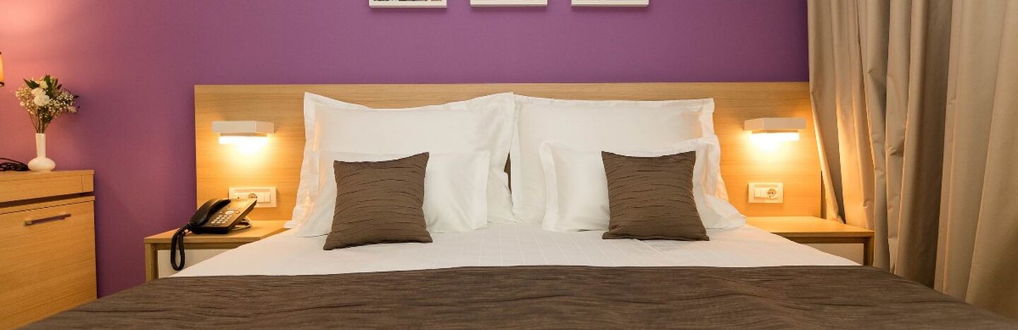 Ein ordentlich gemachtes Bett mit braunem und weißem Bettzeug, zwei Kissen und drei Schwarz-Weiß-Fotos darüber.