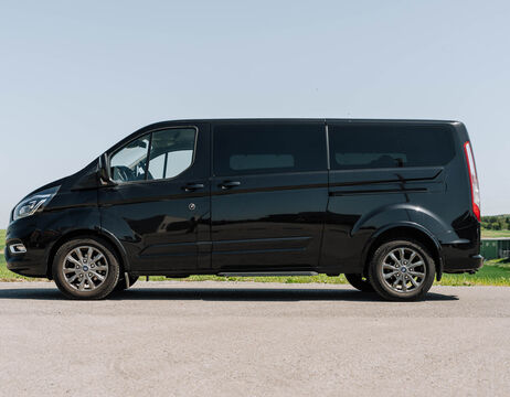 Ein schwarzer Personenkraftwagen, der auf einer Straße geparkt ist, mit einem klaren Himmel im Hintergrund.