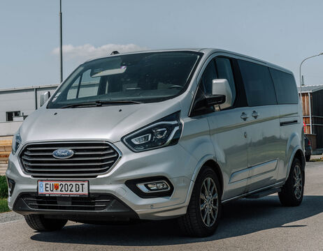 Ein silberner Ford Van ist an einem sonnigen Tag in der Nähe von Industriegebäuden geparkt.