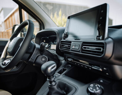 Nahaufnahme des Innenraums eines Autos mit Lenkrad, Schalthebel und Touchscreen-Display auf dem Armaturenbrett.