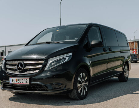 Schwarzer Mercedes-Benz Transporter, der an einem sonnigen Tag im Freien geparkt ist, mit einem BUS 12-Kennzeichen.