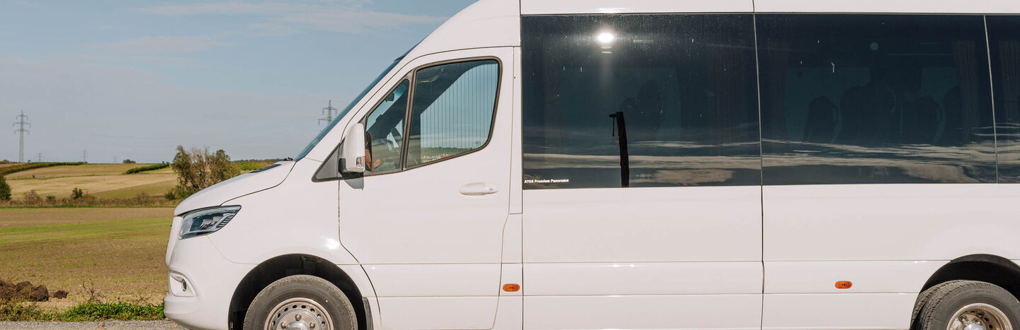 Ein weißer Lieferwagen, der auf einer Landstraße mit Feldern und blauem Himmel im Hintergrund geparkt ist.