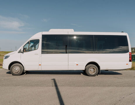 Ein weißer Kleinbus parkt auf einer Straße unter blauem Himmel.