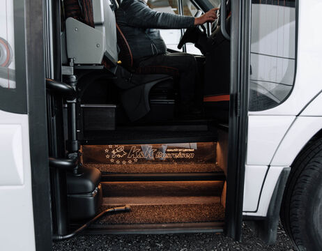 Person, die auf dem Fahrersitz eines Busses sitzt, mit beleuchteten Stufen, die vom Eingang nach oben führen.