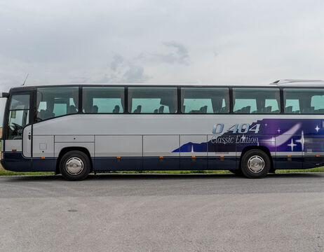 Ein silber-blauer Reisebus, der an einer Straße geparkt ist, mit der Aufschrift O 404 Classic Edition auf der Seite.