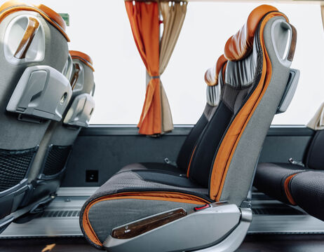 Zwei leere, moderne Bussitze mit orangefarbenen Akzenten und Fenstervorhängen im Hintergrund.