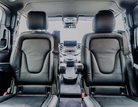 Zwei schwarze Ledersitze in einem modernen Auto, von hinten gesehen mit Blick auf das vordere Armaturenbrett.