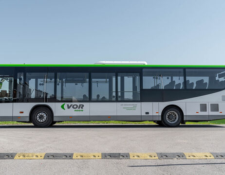 Seitenansicht eines weiß-grünen Stadtbusses, der unter freiem Himmel auf einer Straße geparkt ist.