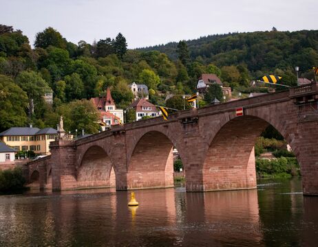 Ein Boot mit Menschen auf einem See, Berge und ein Schloss im Hintergrund unter einem klaren Himmel.