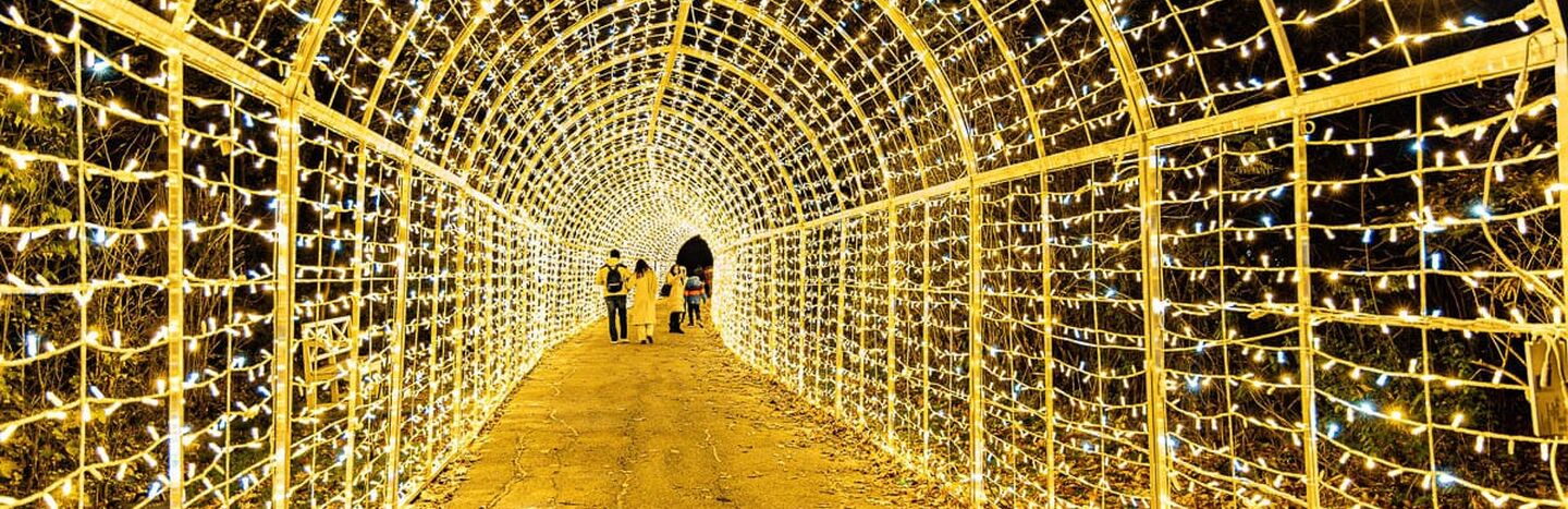 Menschen, die nachts durch einen mit gelben Lichtern beleuchteten Tunnel gehen.
