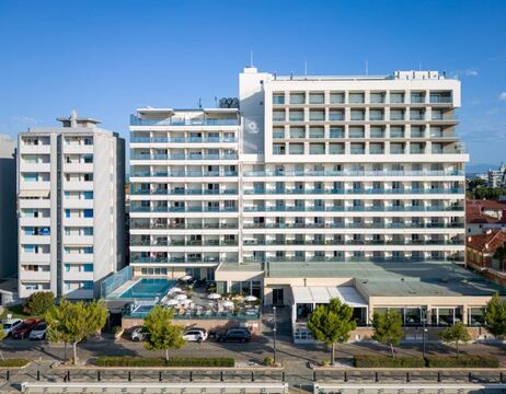 Klippen mit grünen Hängen überblicken ein ruhiges, weitläufiges Gewässer unter einem dramatischen, bewölkten Himmel.