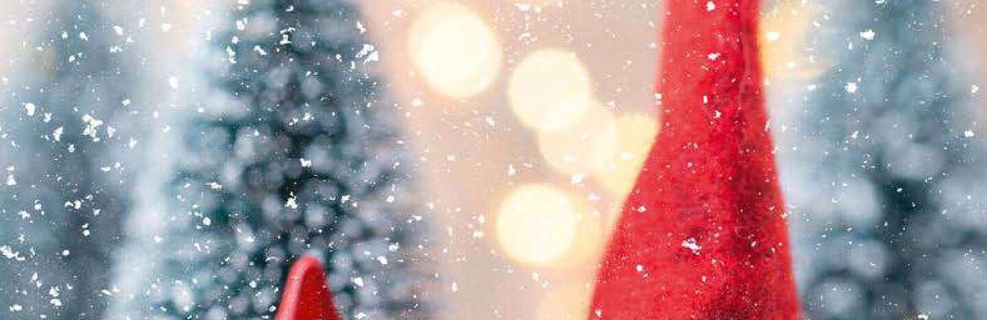 Ein festlicher Gnom mit roter Mütze und Stern sitzt im fallenden Schnee; der Text wirbt für K&K Busreisen Winterreisen.