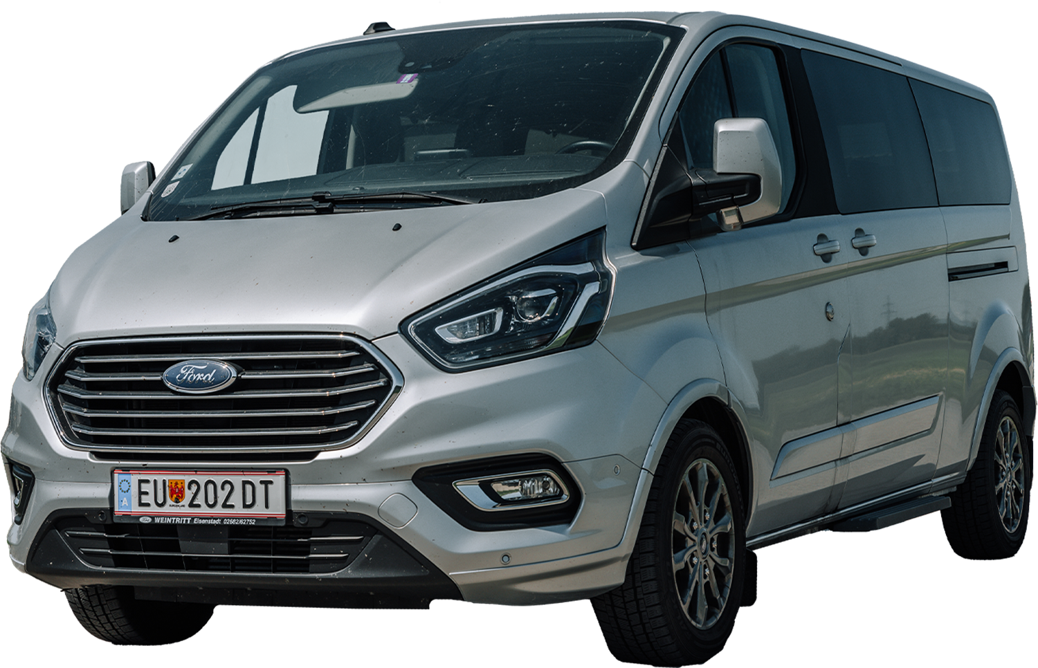 Auf dem Bürgersteig geparkter silberner Ford-Kleintransporter, Vorder- und Seitenansicht, mit europäischem Nummernschild sichtbar.