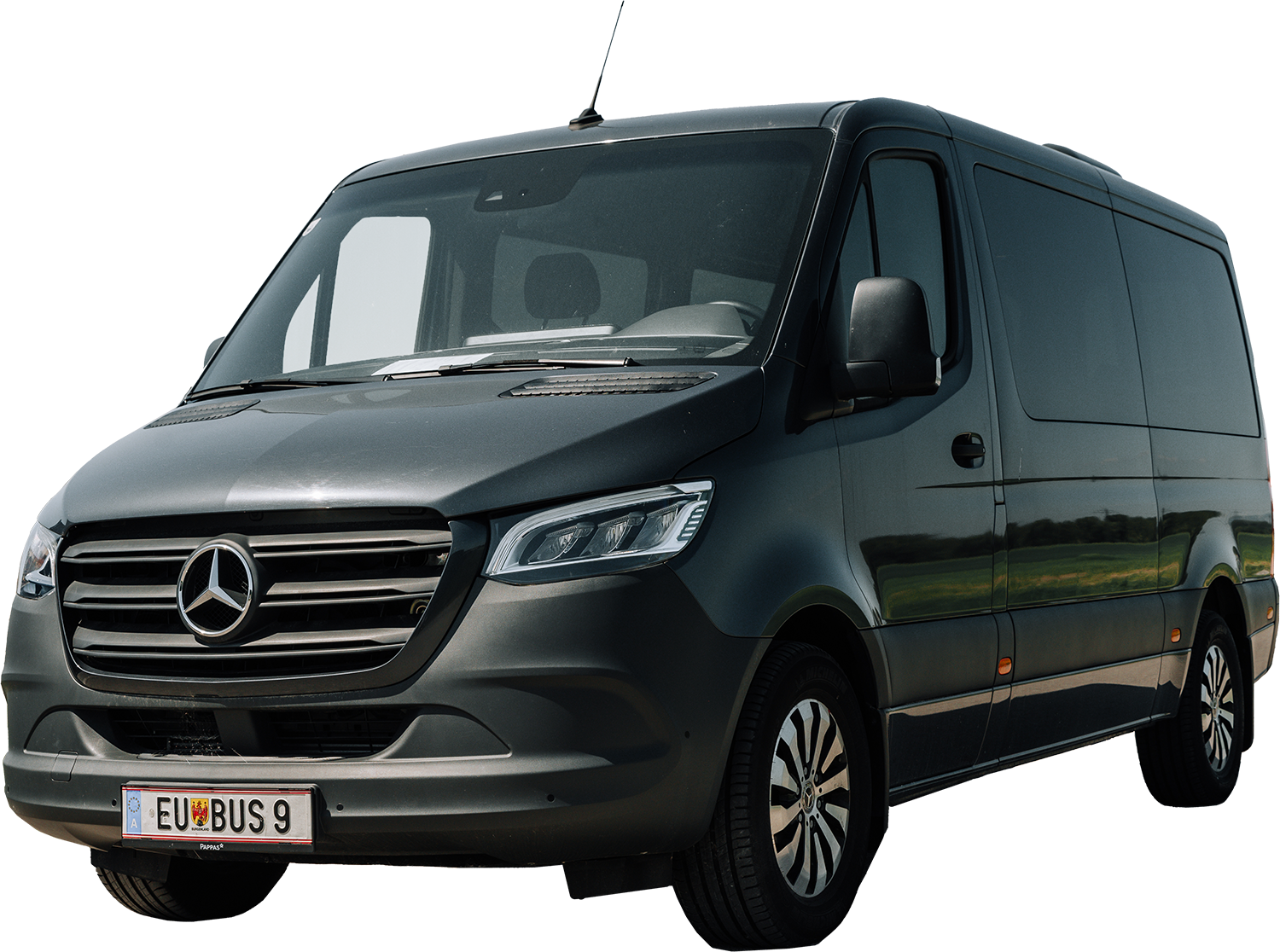 Ein grauer Mercedes-Benz Transporter mit europäischem Kennzeichen, geparkt an einem sonnigen Tag.