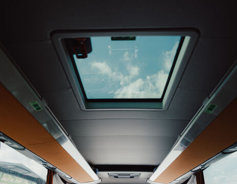 Schloss mit roten Dächern auf einem felsigen Hügel, umgeben von grünem Wald und sanften Hügeln im Hintergrund.