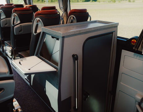 Außenschwimmbad mit roten Sonnenschirmen, Liegestühlen und Menschen, die sich unter einem blauen Himmel entspannen.