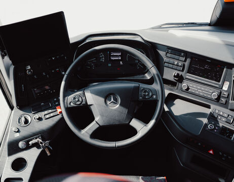 Menschen schwimmen in einem klaren Hotelpool mit Liegestühlen und roten Sonnenschirmen unter einem sonnigen, blauen Himmel.