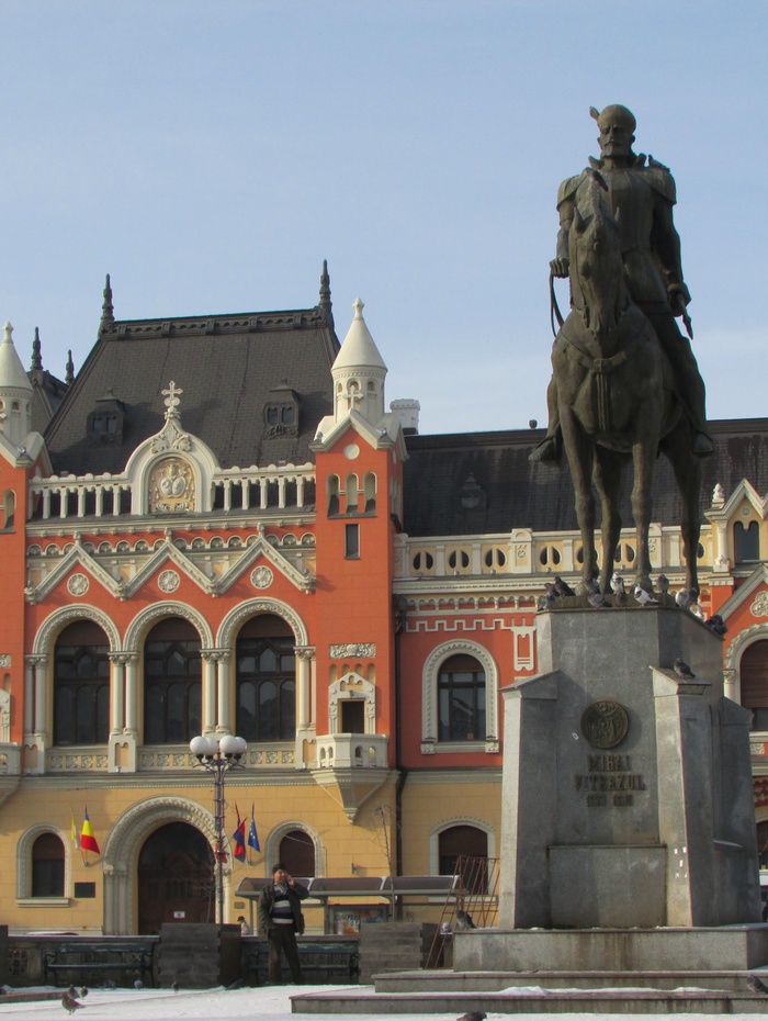 Statue eines Mannes auf einem Pferd vor einem verzierten, farbenfrohen historischen Gebäude mit Bogenfenstern.