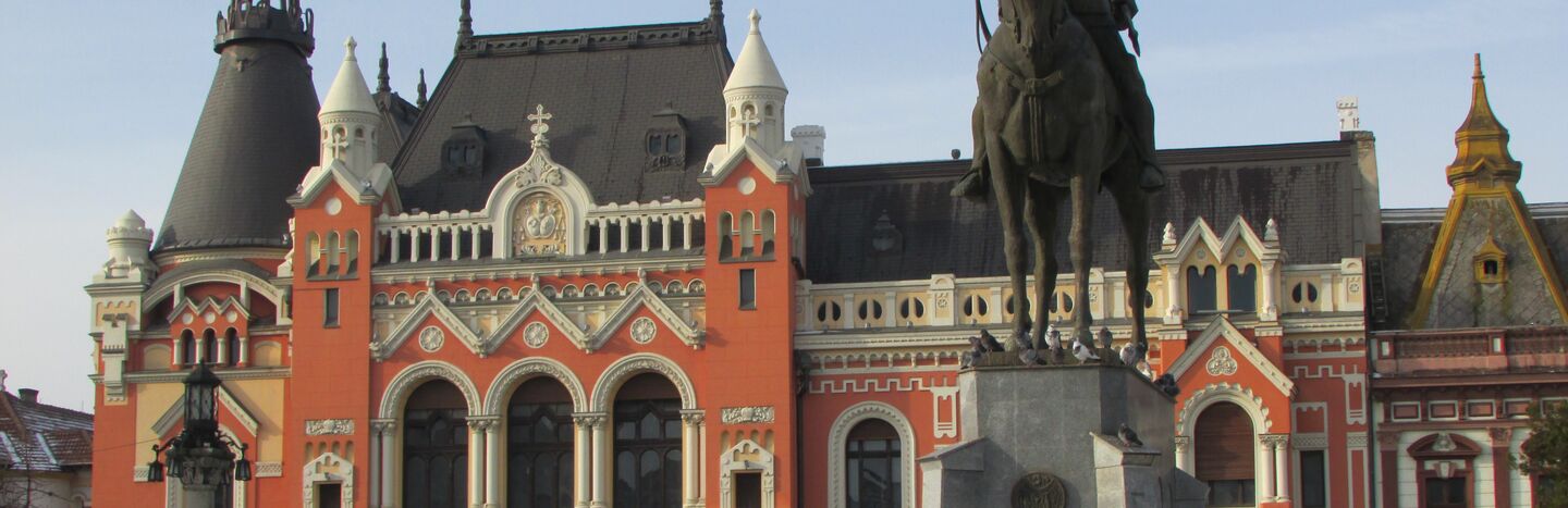 Statue eines Mannes auf einem Pferd vor einem verzierten, farbenfrohen historischen Gebäude mit Bogenfenstern.