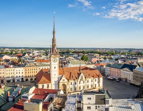 Luftaufnahme eines historischen Rathauses mit einem hohen Uhrenturm auf einem europäischen Stadtplatz.