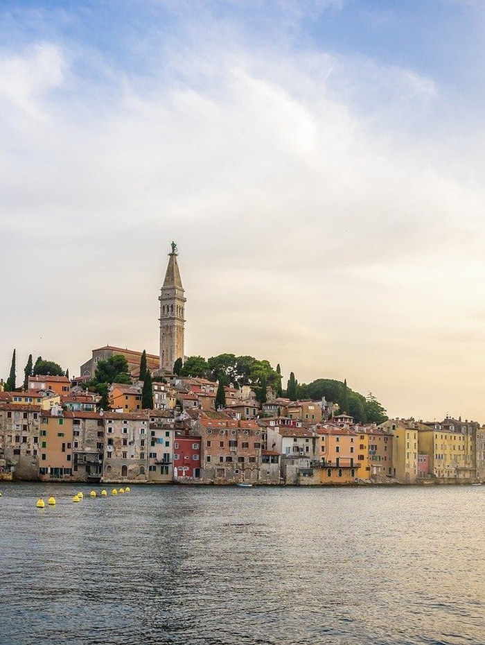 Zwei Fahrräder, die auf einem Kiesweg in einem grasbewachsenen Feld unter einem teilweise bewölkten Himmel abgestellt sind.
