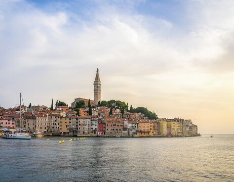 Zwei Fahrräder, die auf einem Kiesweg in einem grasbewachsenen Feld unter einem teilweise bewölkten Himmel abgestellt sind.
