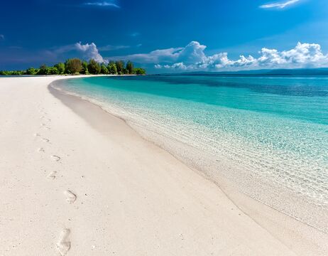 Alte steinerne Abteiruinen mit Bogenfenstern und Grabsteinen auf einer grünen Wiese unter einem teilweise bewölkten Himmel.