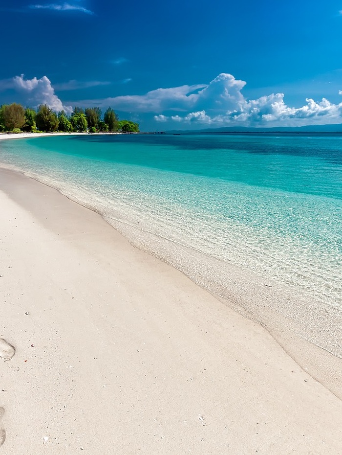 Alte steinerne Abteiruinen mit Bogenfenstern und Grabsteinen auf einer grünen Wiese unter einem teilweise bewölkten Himmel.