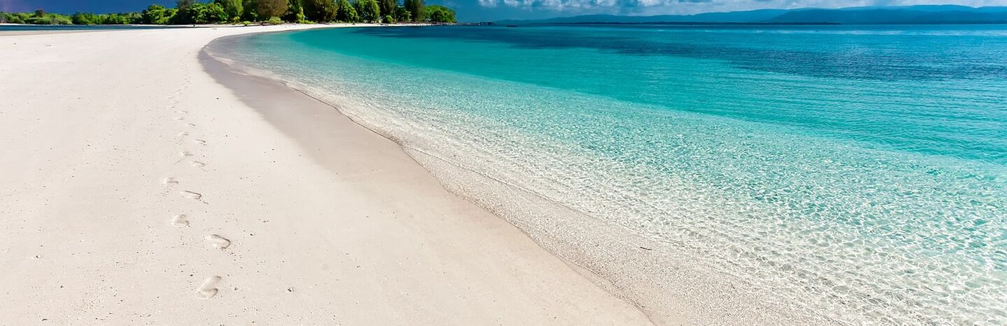 Alte steinerne Abteiruinen mit Bogenfenstern und Grabsteinen auf einer grünen Wiese unter einem teilweise bewölkten Himmel.