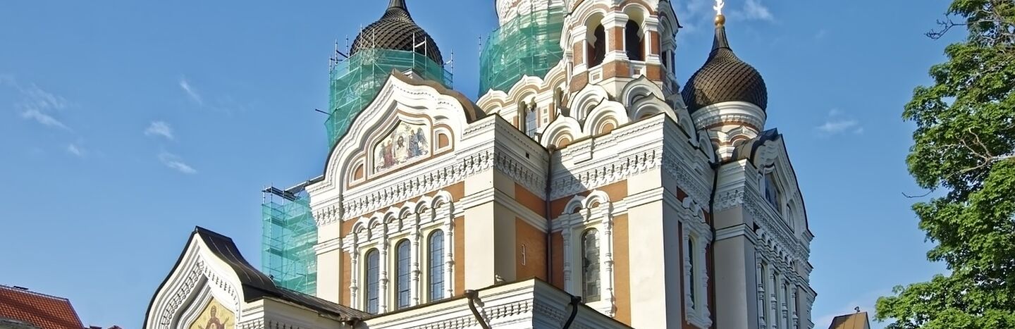 Orthodoxe Kathedrale mit Zwiebeltürmen und Baugerüsten vor einem strahlend blauen Himmel.