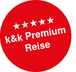 Roter Kreis mit fünf weißen Sternen und darunter der Text k&k Premium Reise in Weiß.