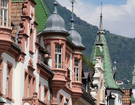 Frau lächelt neben einem geschmückten Weihnachtsbaum mit roten Ornamenten und Lichterketten.
